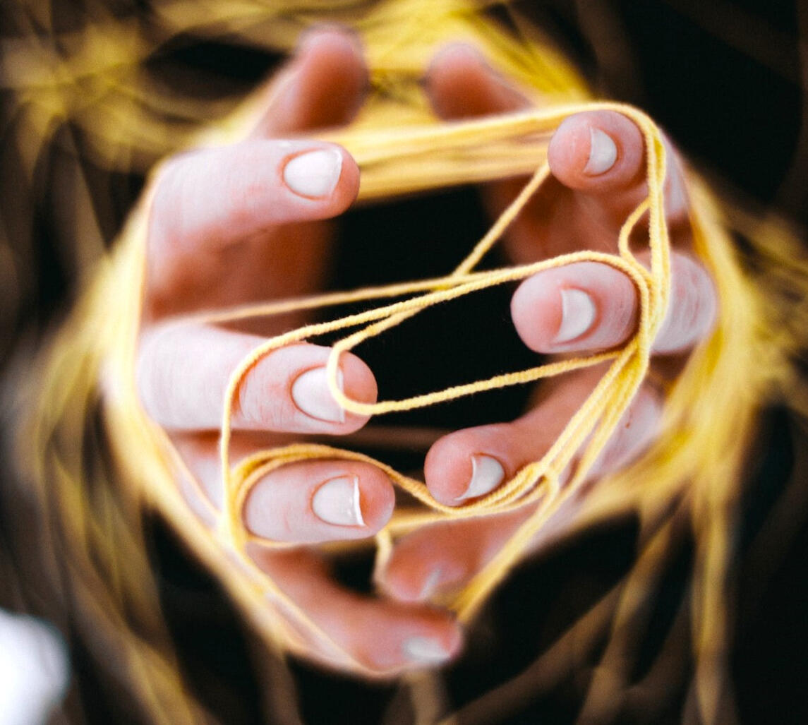 hands kneading through strands of gold yarn photo by Анна Малышева via pexels
